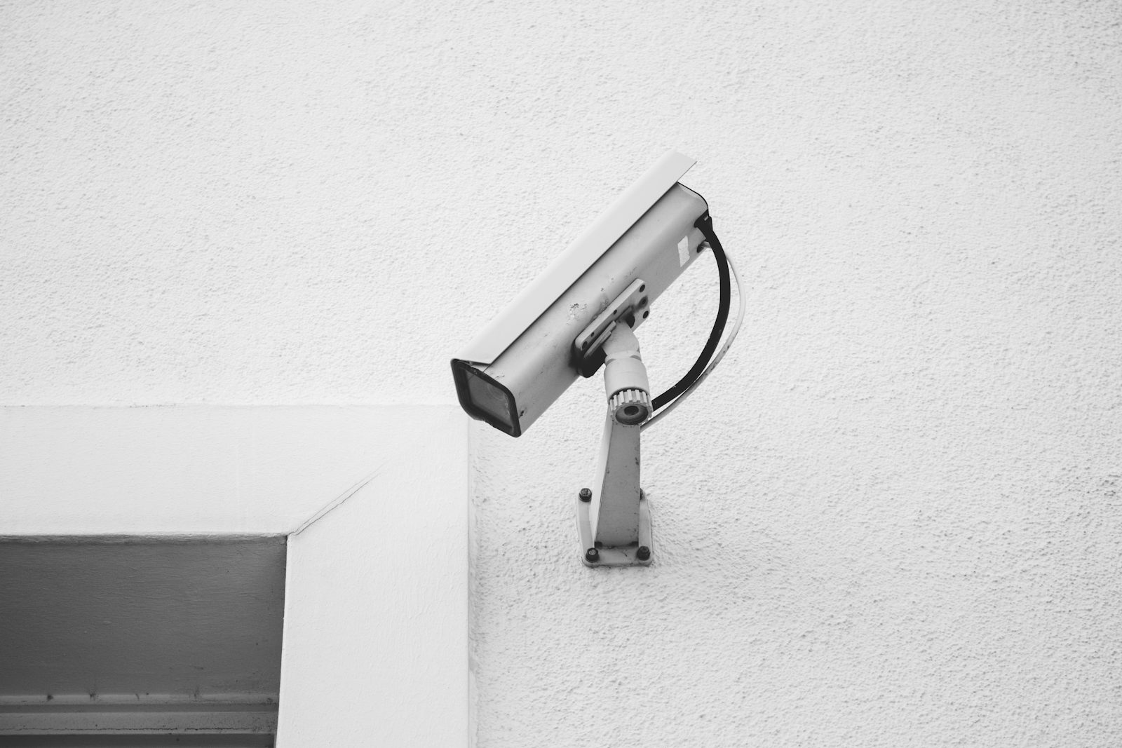 A fixed CCTV camera mounted on a white wall